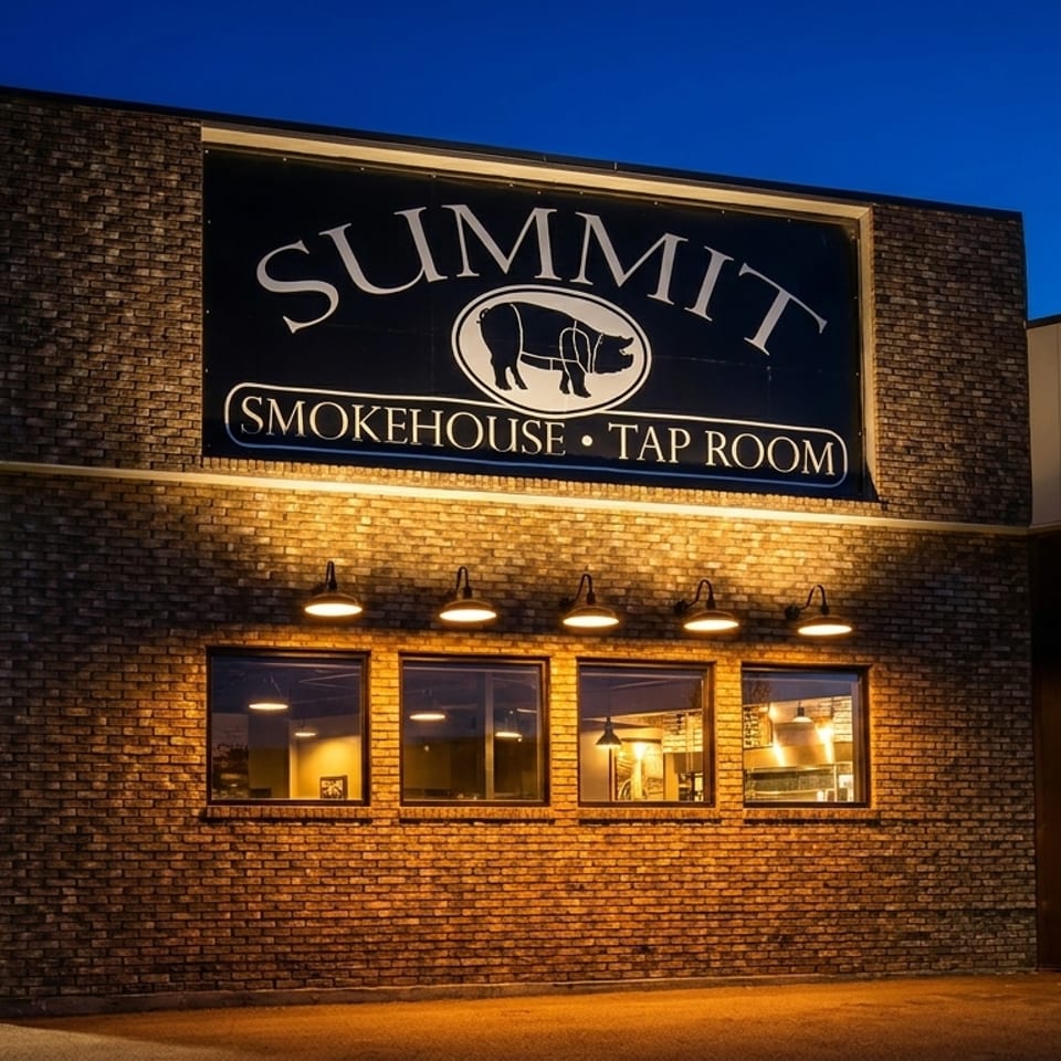 Exterior of Summit Smokehouse & Tap Room at dusk, with illuminated sign and windows.